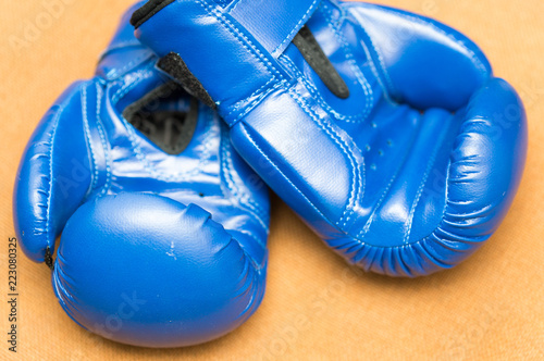 Blue boxing gloves on a brown background fabric © donikz