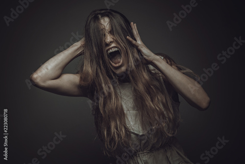 Fotografia Crazy, deranged young woman screaming with frustration, expressing madness and r