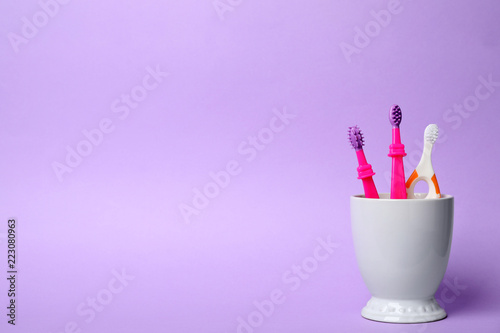 Baby toothbrushes in holder and space for text on color background