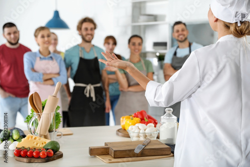 Group of people and female chef at cooking classes photo