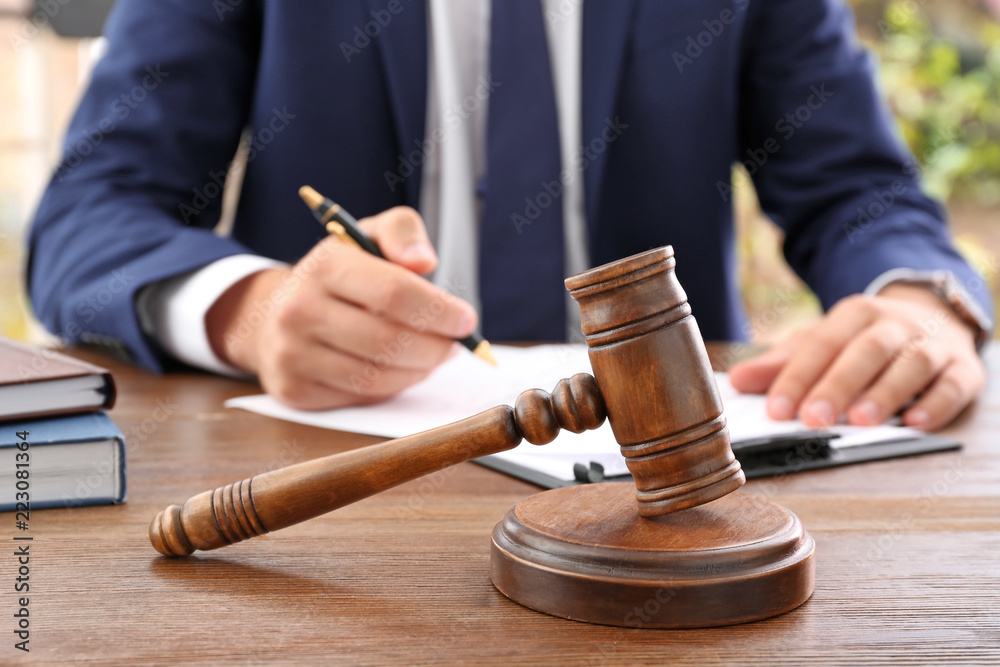 Gavel and blurred lawyer working with documents on background Gavel and blurred lawyer working with documents on background