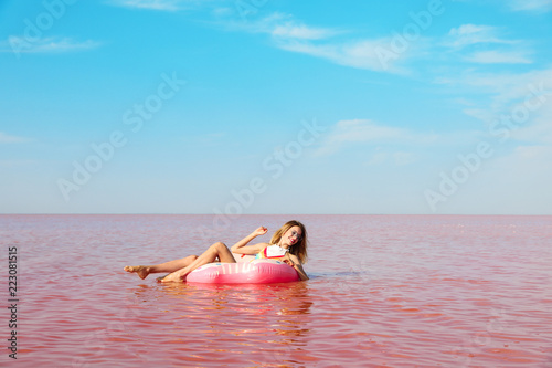 Beautiful woman on inflatable ring in pink lake