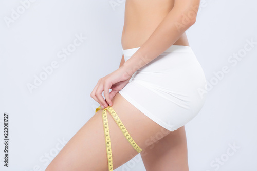 Closeup caucasian leg slim and body of woman with measure isolated on white background, girl with measuring centimeter tape for healthy and diet, cellulite and calories for health care with perfect.