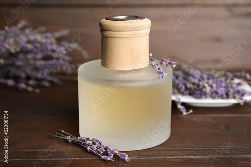 Fototapeta Naklejka Na Ścianę i Meble -  Bottle with aromatic lavender oil on wooden table