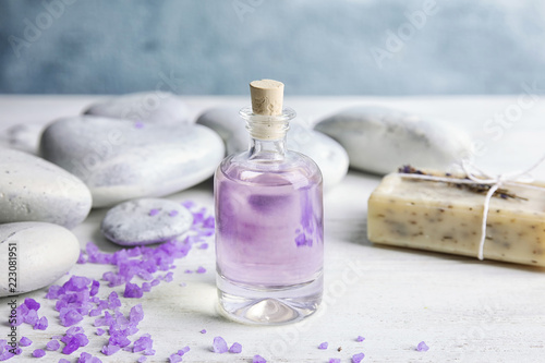 Fototapeta Naklejka Na Ścianę i Meble -  Bottle with natural herbal oil, soap and lavender flowers on table against blurred background