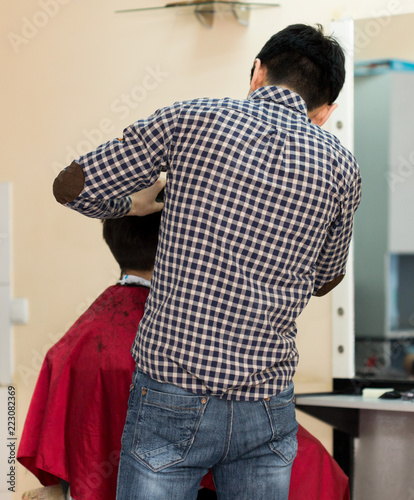 hairdresser cuts client's hair. Rear view of man in the barber shop.
