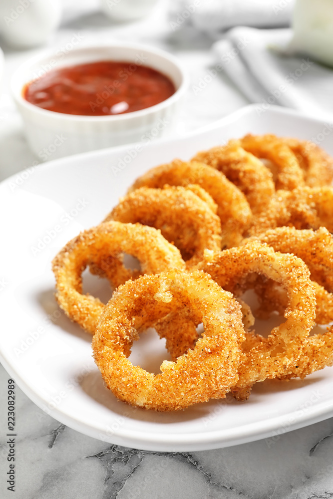 Plate with homemade crunchy fried onion rings and sauce on marble table, closeup Plate with homemade crunchy fried onion rings and sauce on marble table, closeup