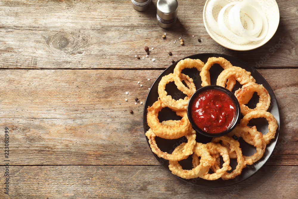 Homemade crunchy fried onion rings with tomato sauce on wooden table, top view. Space for text Homemade crunchy fried onion rings with tomato sauce on wooden table, top view. Space for text