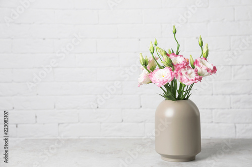 Beautiful flowers in vase and space for text on blurred background. Element of interior design
