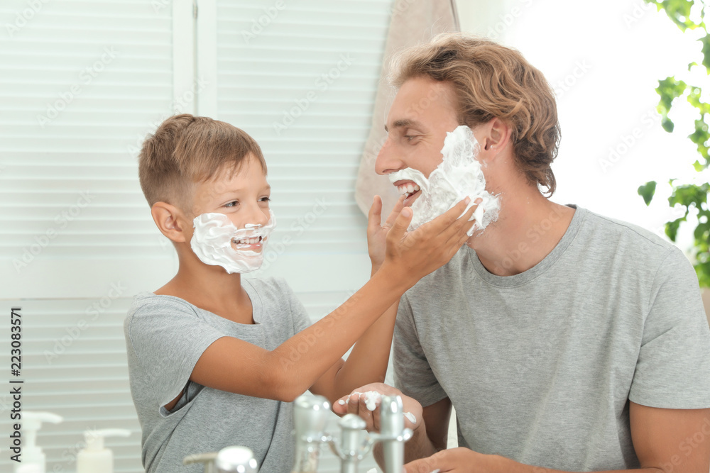 Father and son applying shaving foam in bathroom Father and son applying shaving foam in bathroom
