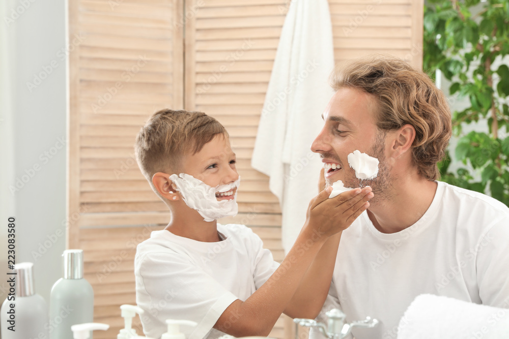 Father and son applying shaving foam in bathroom Father and son applying shaving foam in bathroom