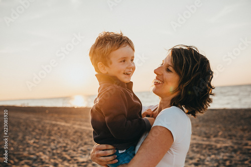 Pregnant Mother And Her Little Boy At The Beach At Sunset