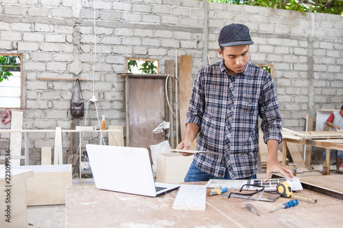 young carpenter checking material samples using internet on lapt