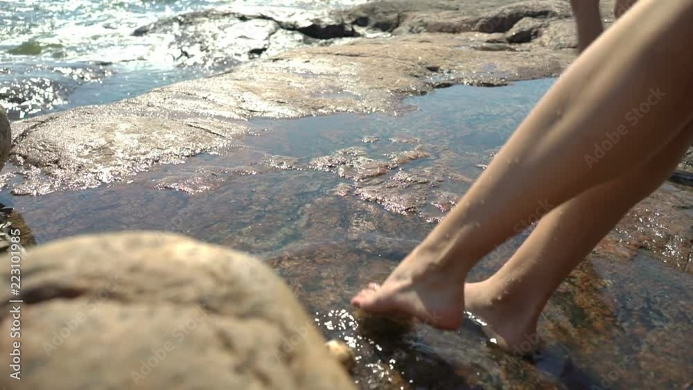 A young slender woman and her sweet daughter are playing in rock pools among the coastal rocks on the beach in Finland. A young slender woman and her sweet daughter are playing in rock pools among the coastal rocks on the beach in Finland.