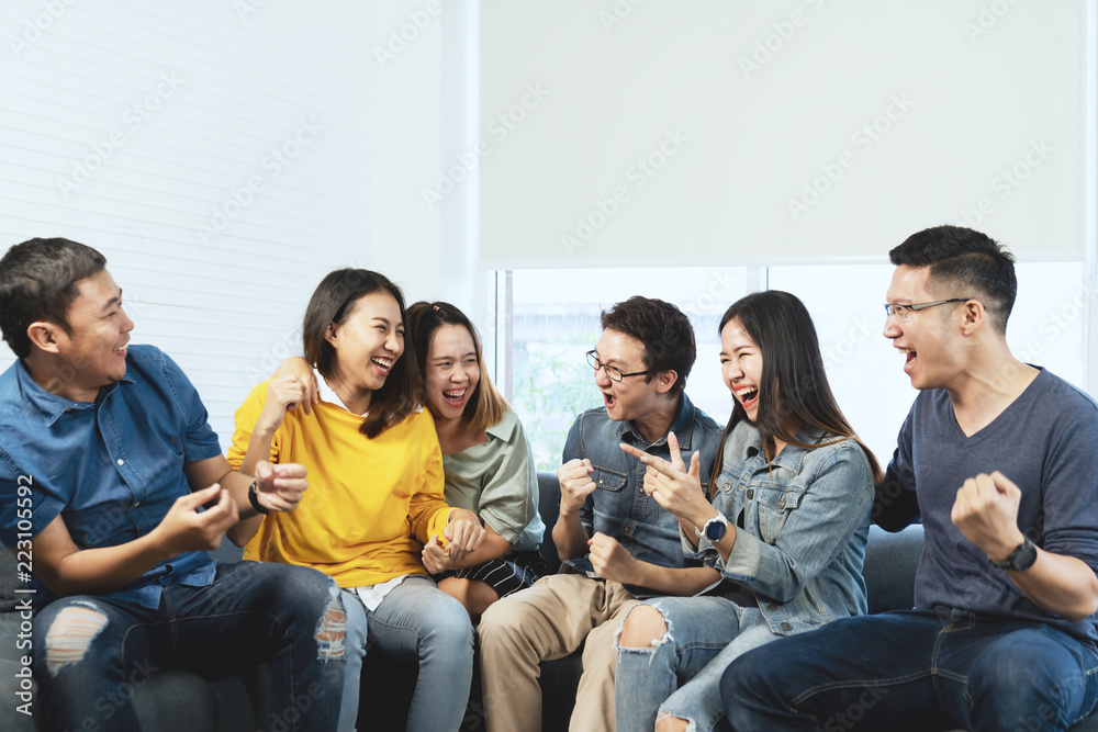 Young Attractive asian group of friends talking and laughing with happy in gathering meeting sitting at home feeling cheerful and enjoy game in leisure time together. People in blue or yellow wearing. - obrazy, fototapety, plakaty 