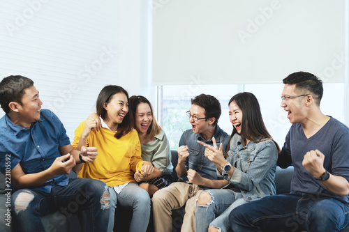 Young Attractive asian group of friends talking and laughing with happy in gathering meeting sitting at home feeling cheerful and enjoy game in leisure time together. People in blue or yellow wearing.