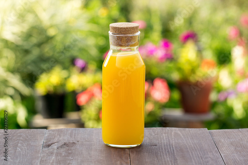 Mango juice and orange in a glass bottle. Beautiful green garden background