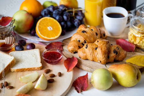 Autumn time. Season leaf fall. Orange juice in a glass bottle. Coffee in the French press. Breakfast with croissant. Good start to the day. Good morning.