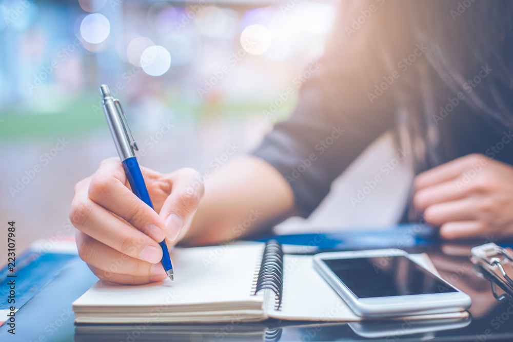 Woman hand writing on a notebook.with a pen.