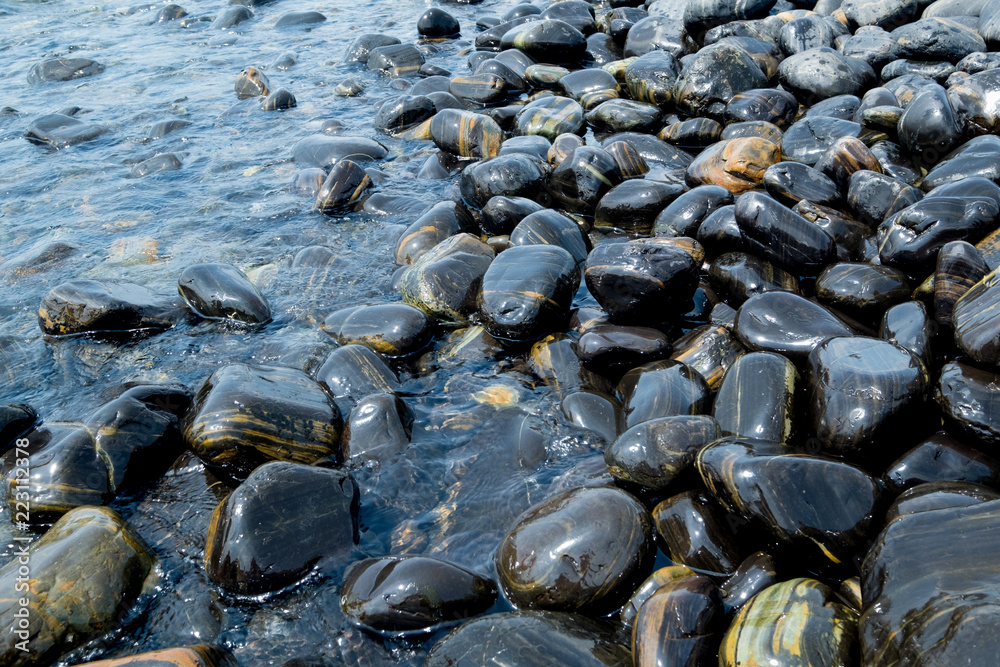 Obraz premium Beautiful wet black stones at Koh Hin Ngam in summer time concept travel, holiday and vacation. Tropical paradise beach nature landscape at Lipe island in Thailand