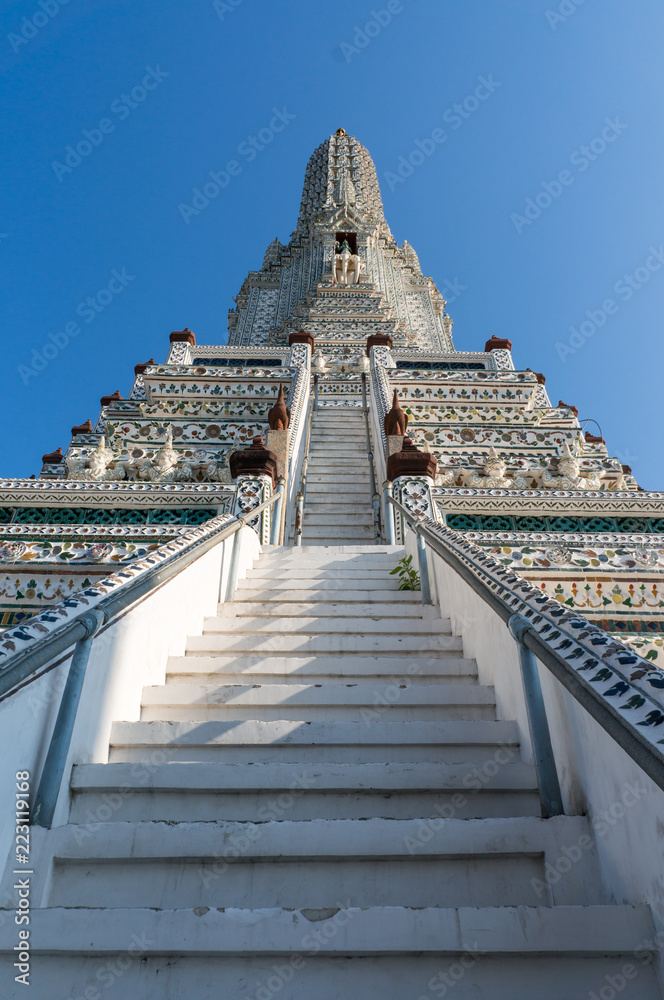 Looking up on a tall temple in Wat Arun on a sunny day with a clear blue sky