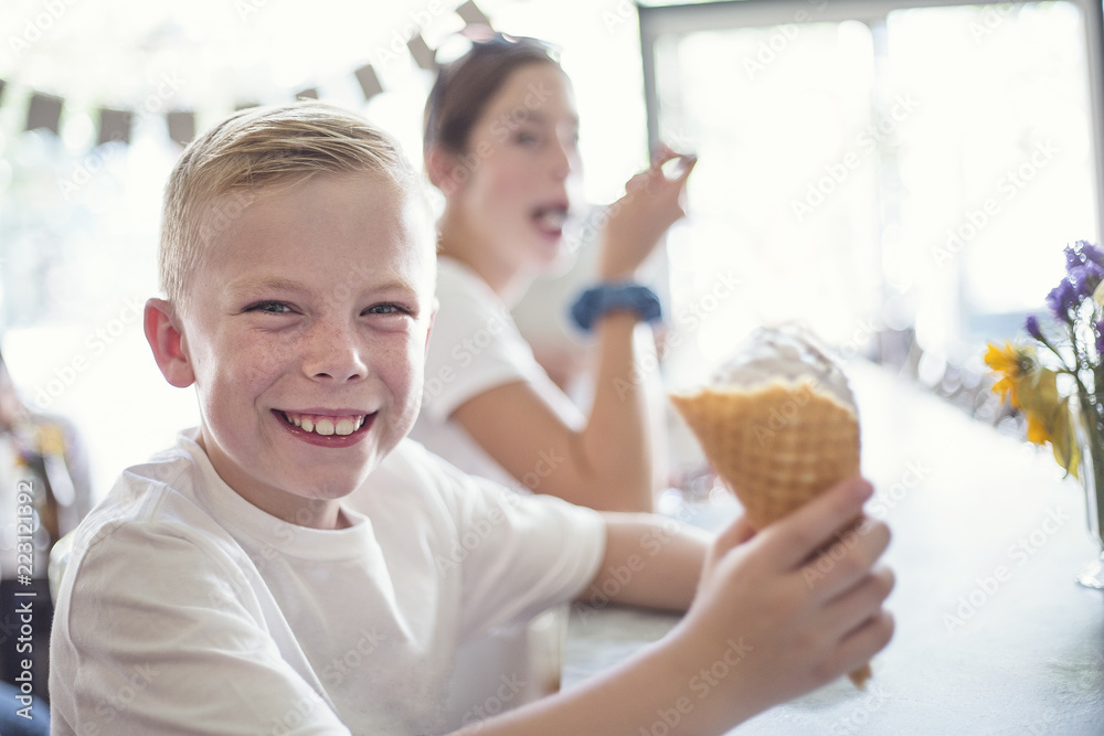 Smiling Children enjoying ice cream cones at an ice cream parlor. Little boy with a waffle cone is enjoying some delicious ice cream