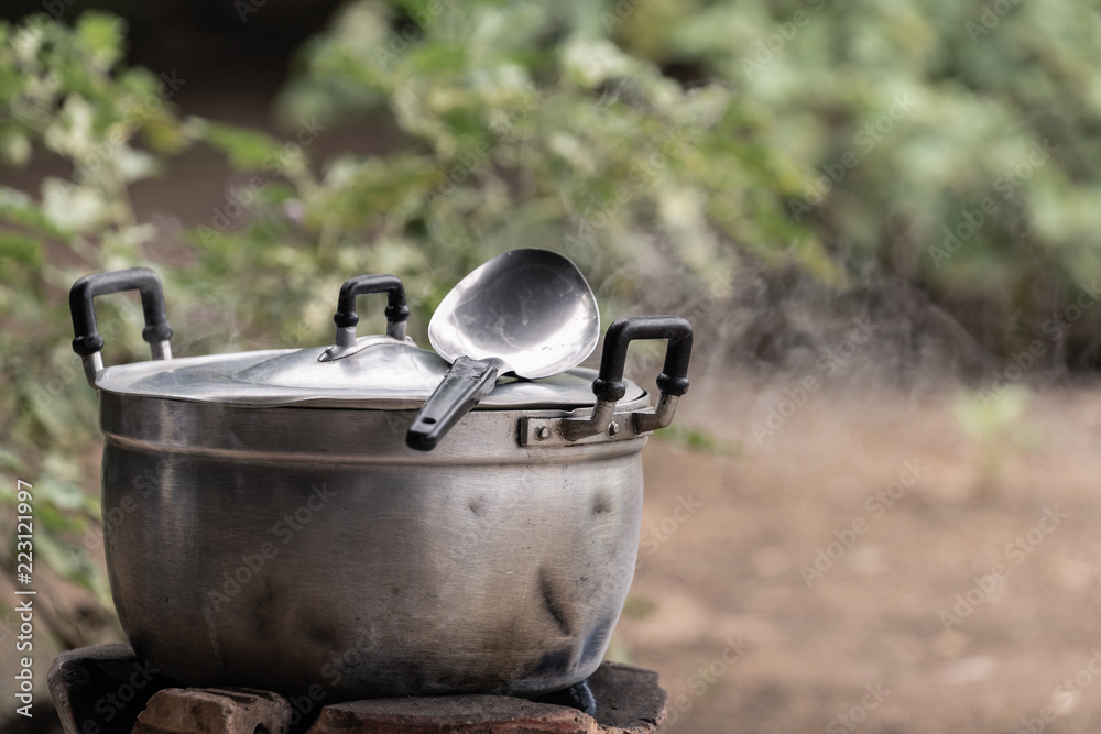 stainless pot cooking with ladle in morning light with smoke stainless pot cooking with ladle in morning light with smoke