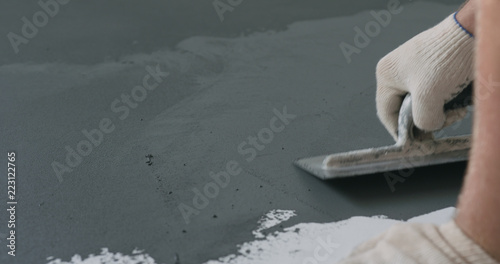 closeup male worker applying micro concrete plaster coating on the floor with a trowel