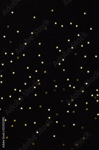 Closeup of golden small stars on black background. Winter, Christmas celebration, holidays season concept