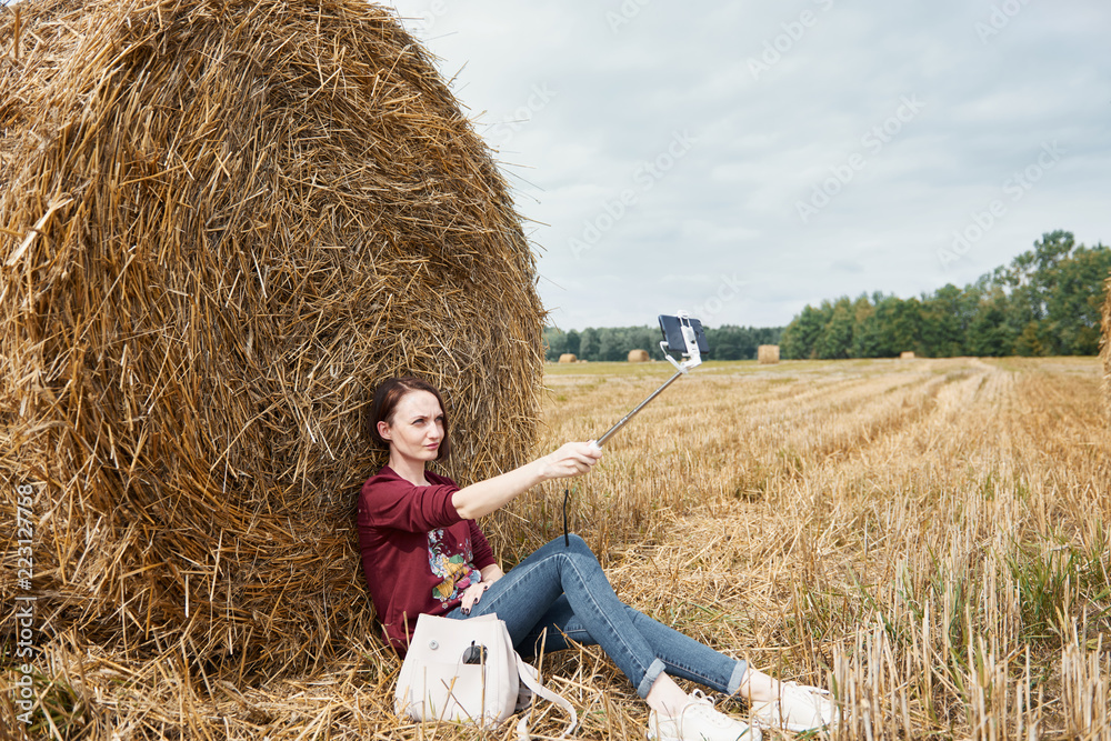 young girl makes selfie on smartphone on the background of haystack young girl makes selfie on smartphone on the background of haystack