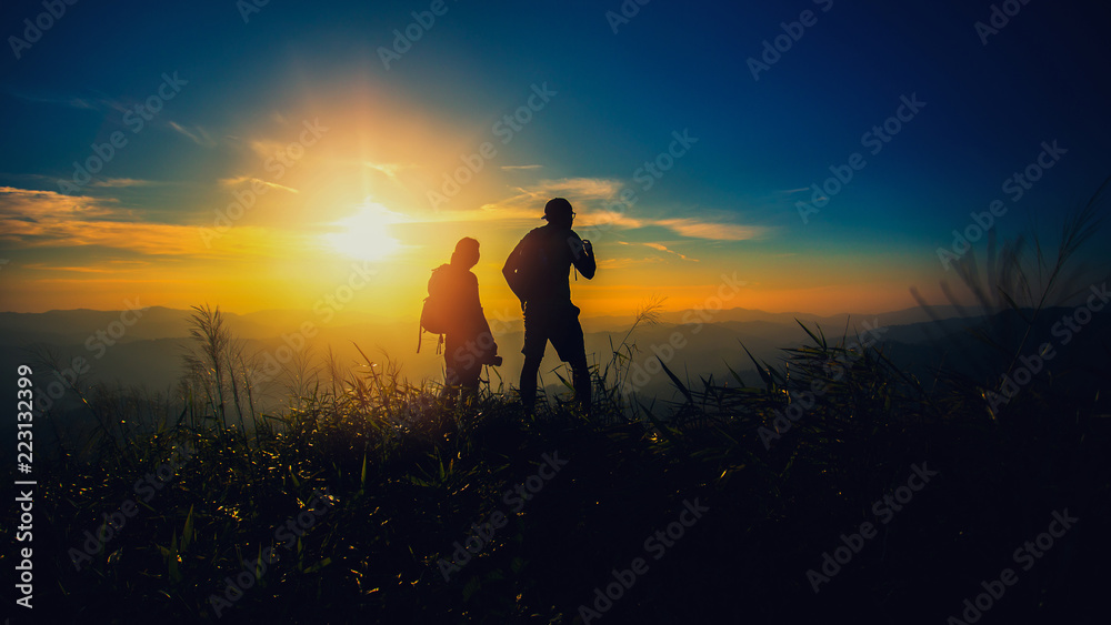 silhouette couple hiker watching through binoculars on the top of mountain