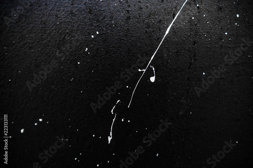 Texture of white paint on a black wall, graffiti, street art. Traces of paintbrush and brush