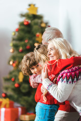 grandparents embracing with kids on christmas at home