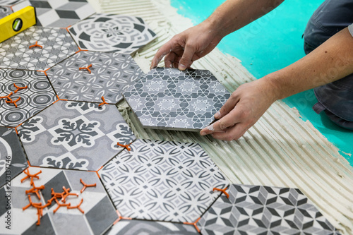 flooring - man laying hexagon tiles on the floor