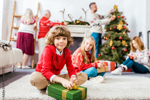 smiling siblings sititng on floor together with gifts during christmas eve