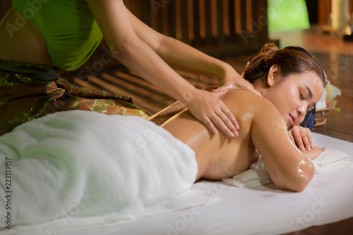 Young Asia beautiful woman during massage with spa herbal compress with oil and herbal set near site, relaxing and healthy concept.