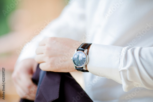 Businessman checking time on his wristwatch. men's hand with a watch. Groom preparing to wedding day
