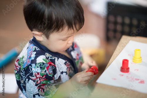 Little toddler boy draw pictures on a paper by use pencil