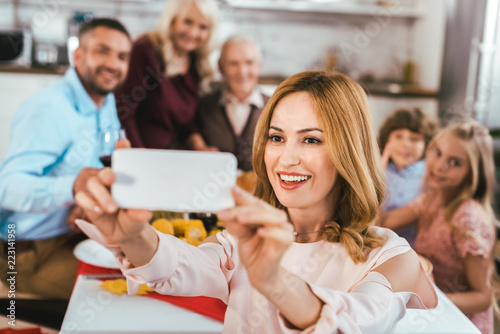 happy young woman taking selfie with her family during thanksgiving dinner © LIGHTFIELD STUDIOS