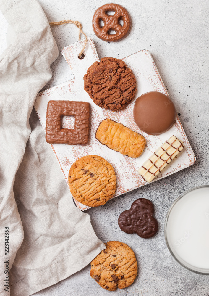 Plakat Oat and chocolate cookies selection with glass of milk on wooden board on stone kitchen table background.