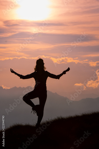Girl practices yoga positions in the mountains during an excursion