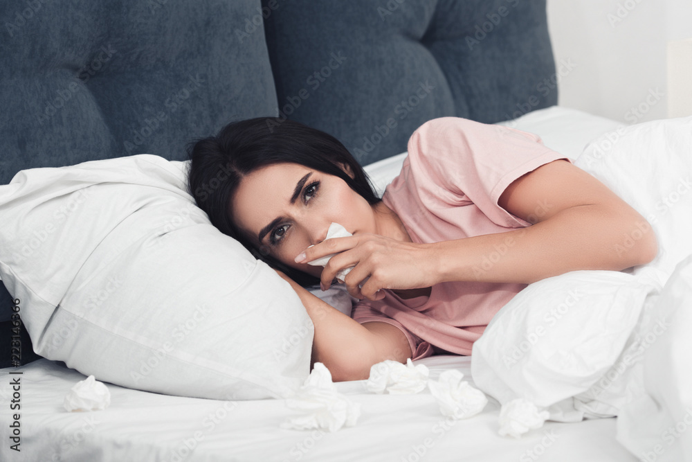 close-up shot of sick young woman with runny nose lying in bed with napkins close-up shot of sick young woman with runny nose lying in bed with napkins