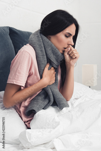 Fotografía sick young woman sitting in bed and having cough