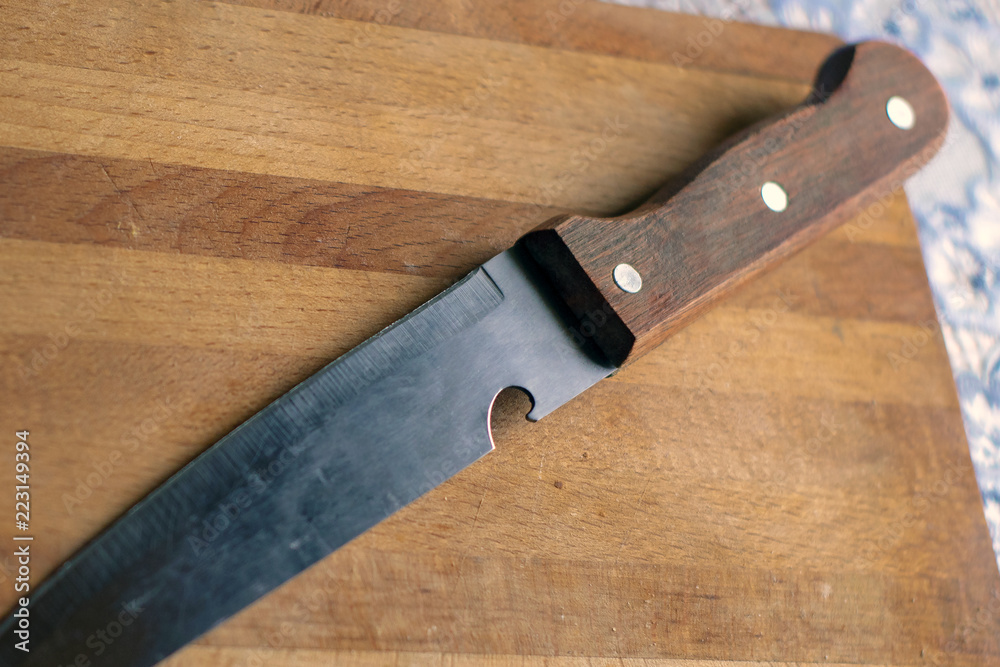 Knife with a wooden handle on a rustic kitchen cutting board