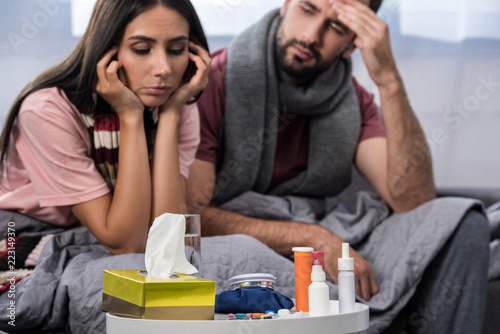 sick couple with meds on table sitting together on couch photo