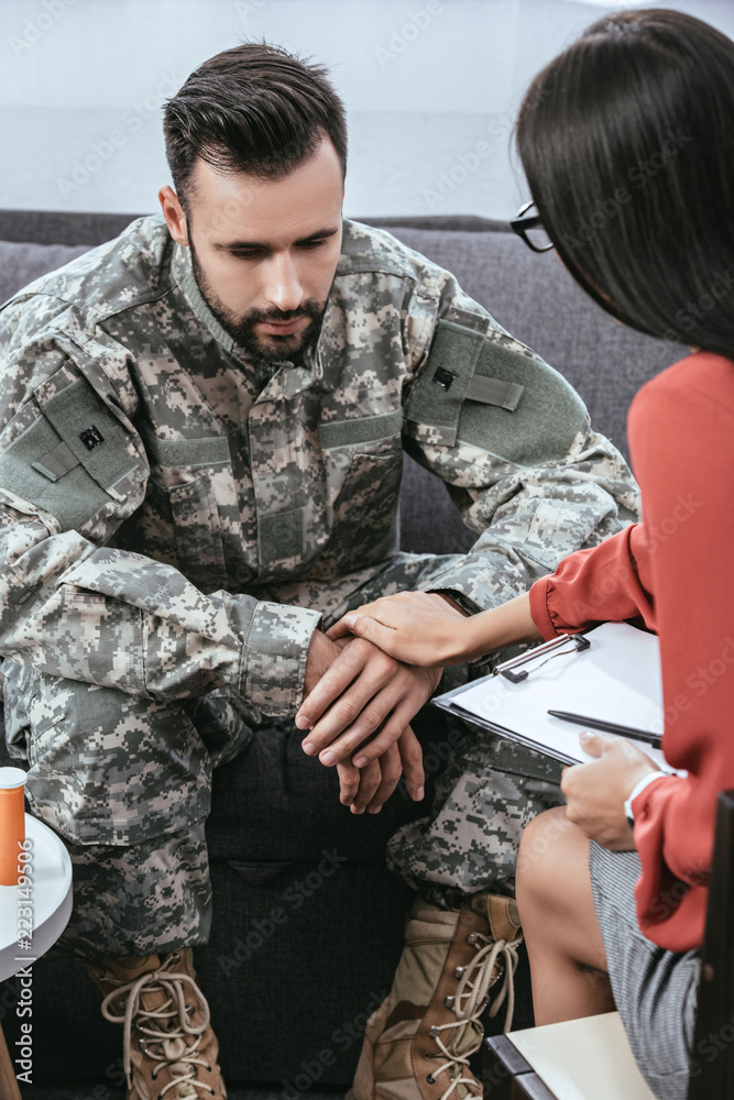 female psychiatrist supporting depressed soldier with post traumatic syndrome during therapy session