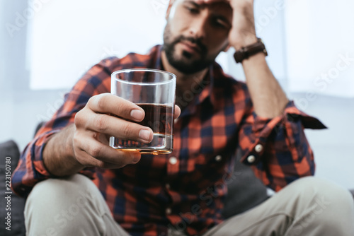 close-up shot of depressed young man with glass of whiskey photo