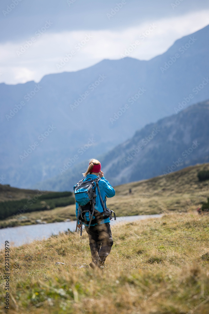 Junge Frau mit Rucksack wandert in den Alpen, Alpensee