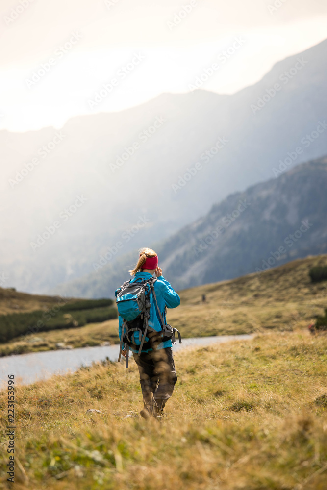 Junge Frau mit Rucksack wandert in den Alpen, Alpensee Junge Frau mit Rucksack wandert in den Alpen, Alpensee