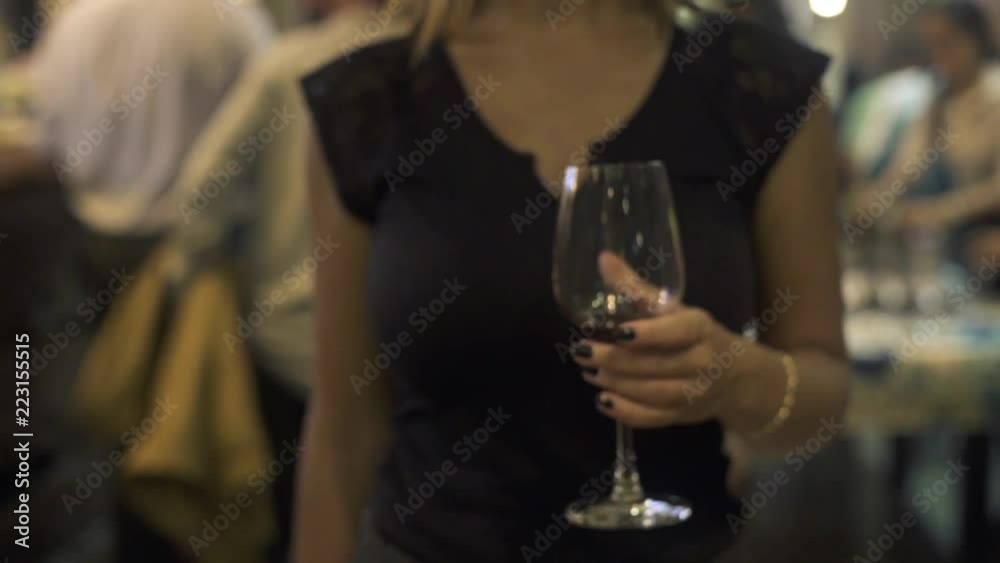 Woman in black clothes holding red wine glass in hands in restaurant. Close up woman with red wineglass. Woman in black clothes holding red wine glass in hands in restaurant. Close up woman with red wineglass.